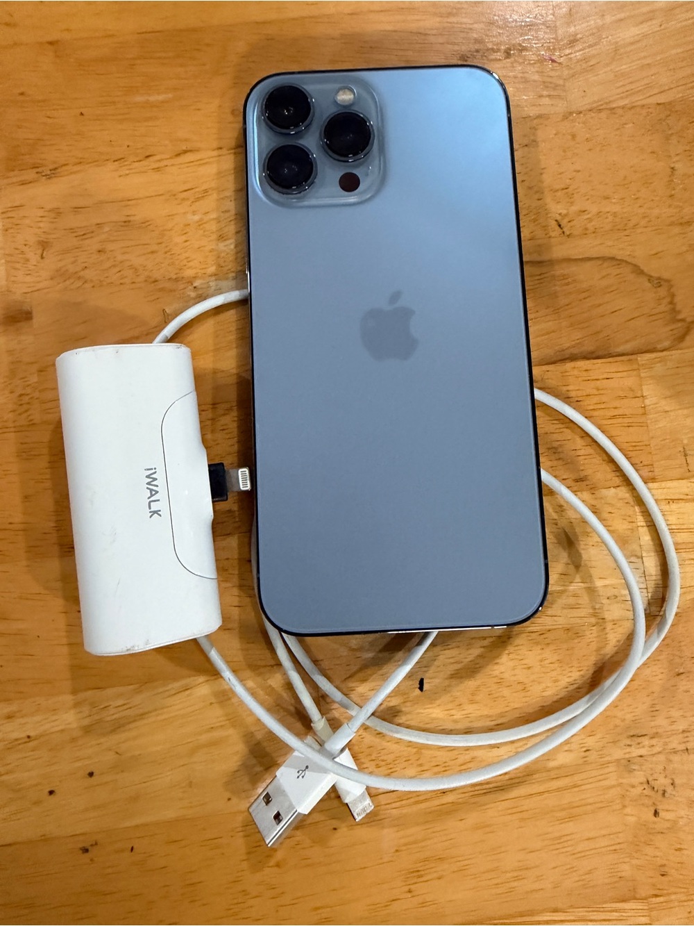 Apple iPhone 13 Pro Max with Sierra Blue Back and white portable charger